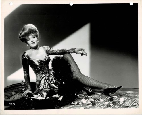 A VINTAGE BLACK & WHITE GLAMOUR PHOTOGRAPH of the Hollywood Movie Star MARLENE DIETRICH in a glossy low cut dress and black fishnet stockings.