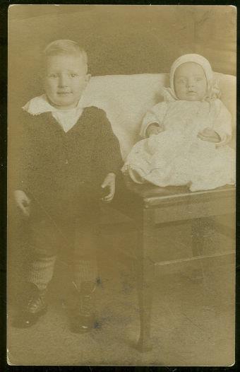REAL PHOTO POSTCARD OF LITTLE BOY STANDING NEXT TO BABY