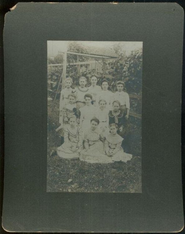 FRAMED PHOTOGRAPH OF GROUP OF YOUNG GIRLS AND TEACHER POSING OUTSIDE