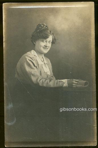 REAL PHOTO POSTCARD OF MADGE SITTING AT A TABLE