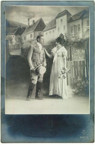 PHOTO POSTCARD OF ROMANTIC COUPLE DRESSED UP IN FRONT OF A PAINTED SET